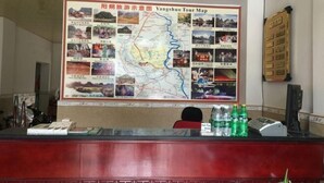 A reception desk with a large Yangshuo Tour Map above it, a computer, and a few bottles of water. - Wonton Hotel Yangshuo (Yangshuo)