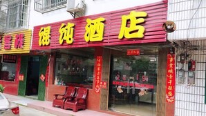 A hotel with a red and yellow facade, a visible entrance, and a few chairs outside. - Wonton Hotel Yangshuo (Yangshuo)