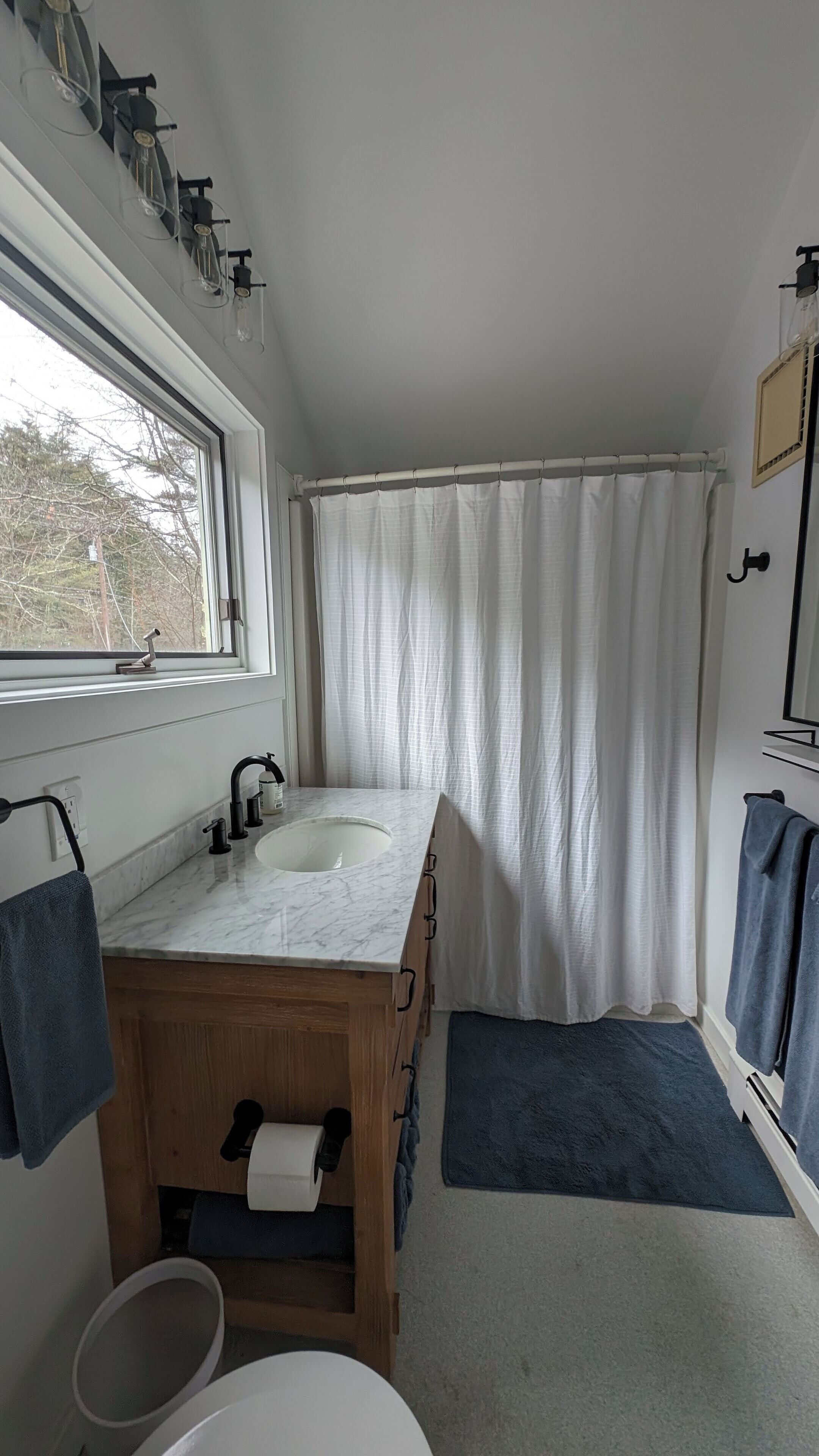 A bathroom with a window, a sink, a mirror, and a shower curtain.