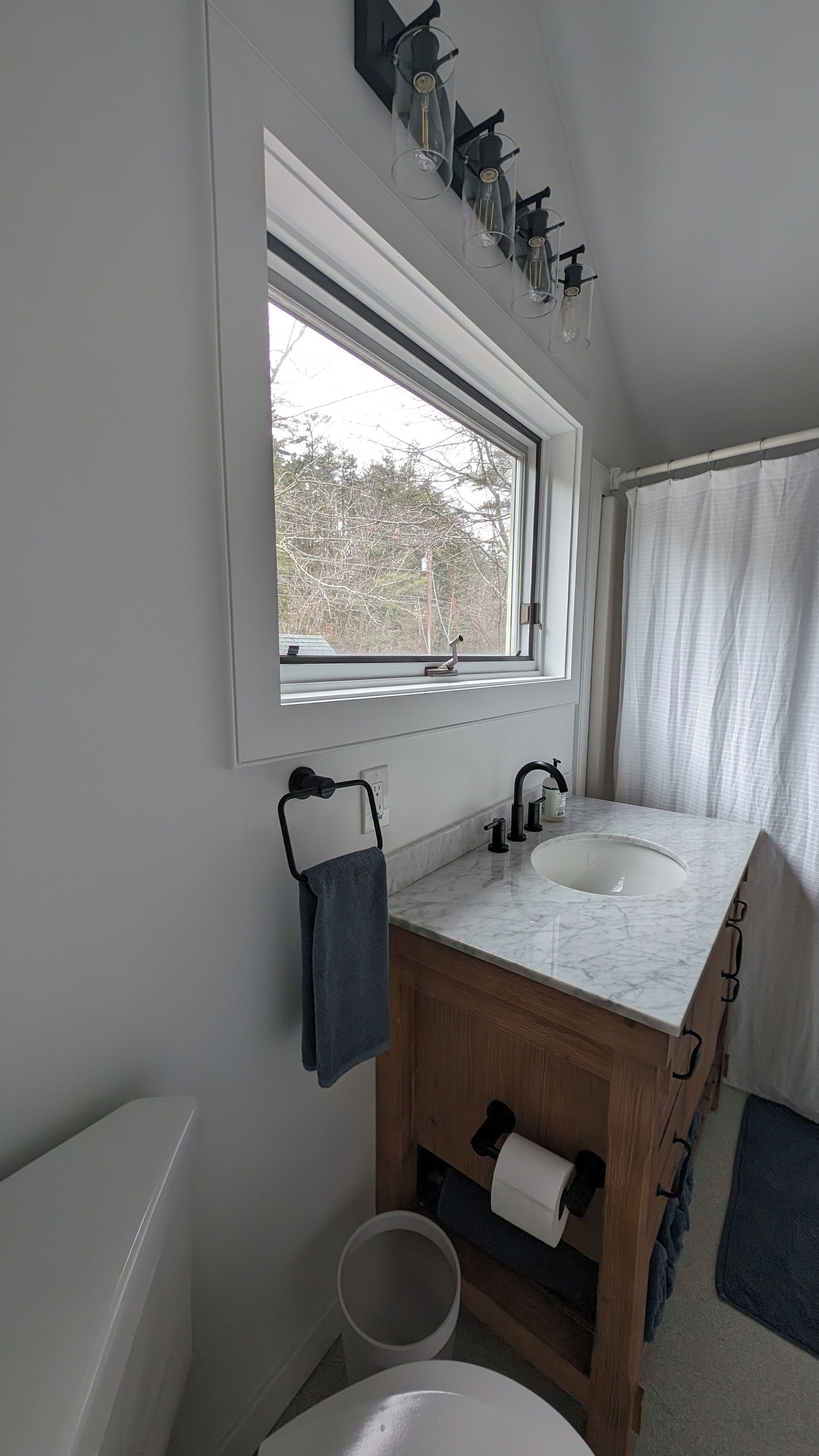 Une salle de bain avec un double vasque, un meuble-lavabo en bois, une fenêtre avec vue et un porte-serviettes.