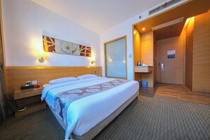 A hotel room with a large bed, a bedside table with a lamp, a wall-mounted artwork, and a door leading to a bathroom. - Haodifang Business Hotel (Quanzhou)