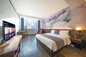 A hotel room with a large bed, a TV on a wooden table, and a painting on the wall. - Haodifang Business Hotel (Quanzhou)