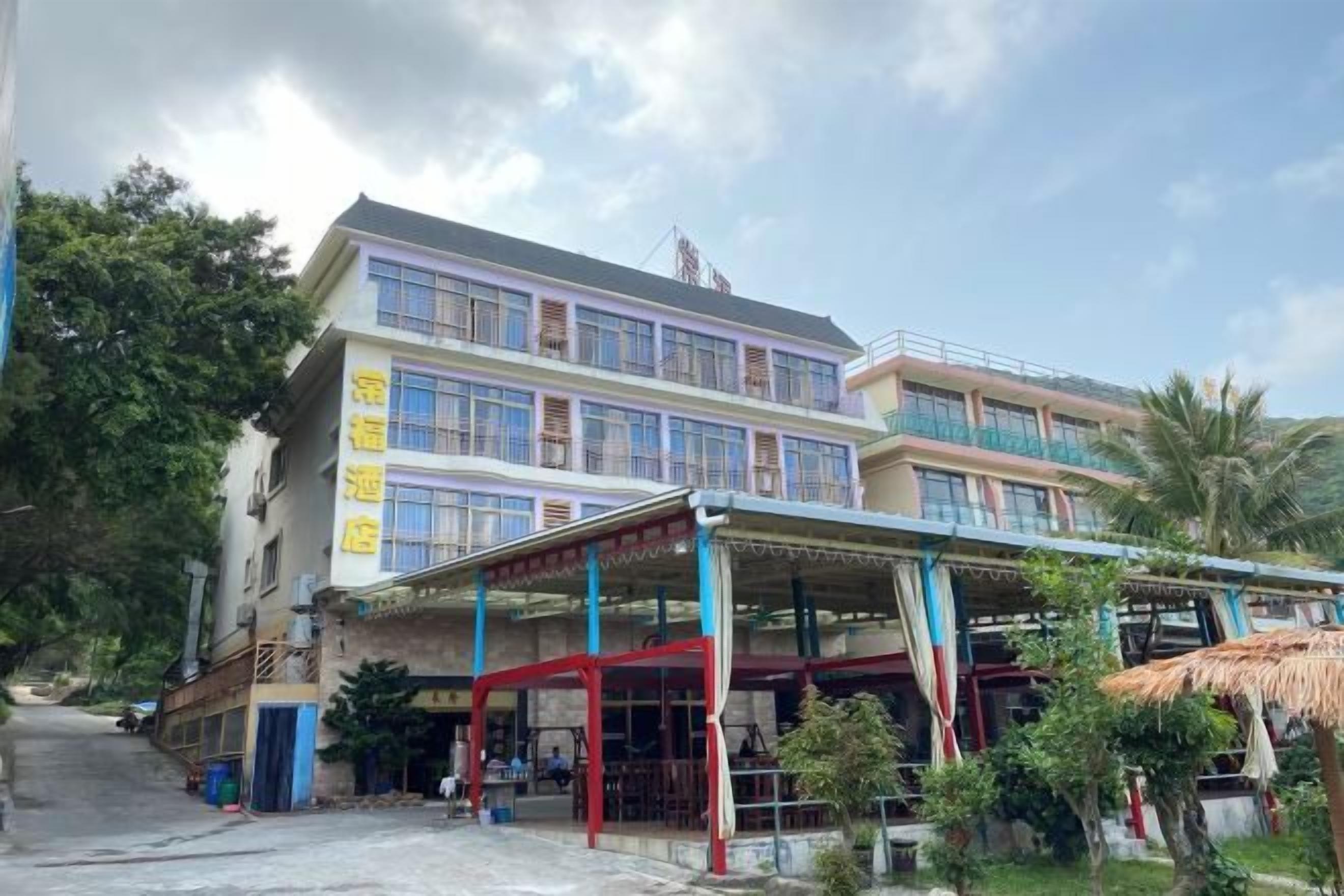 A multi-story building with a covered outdoor seating area and a staircase leading to the entrance.