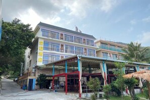 Un edifici de diversos pisos amb una zona d'estar a l'exterior coberta i una escala que porta a l'entrada.