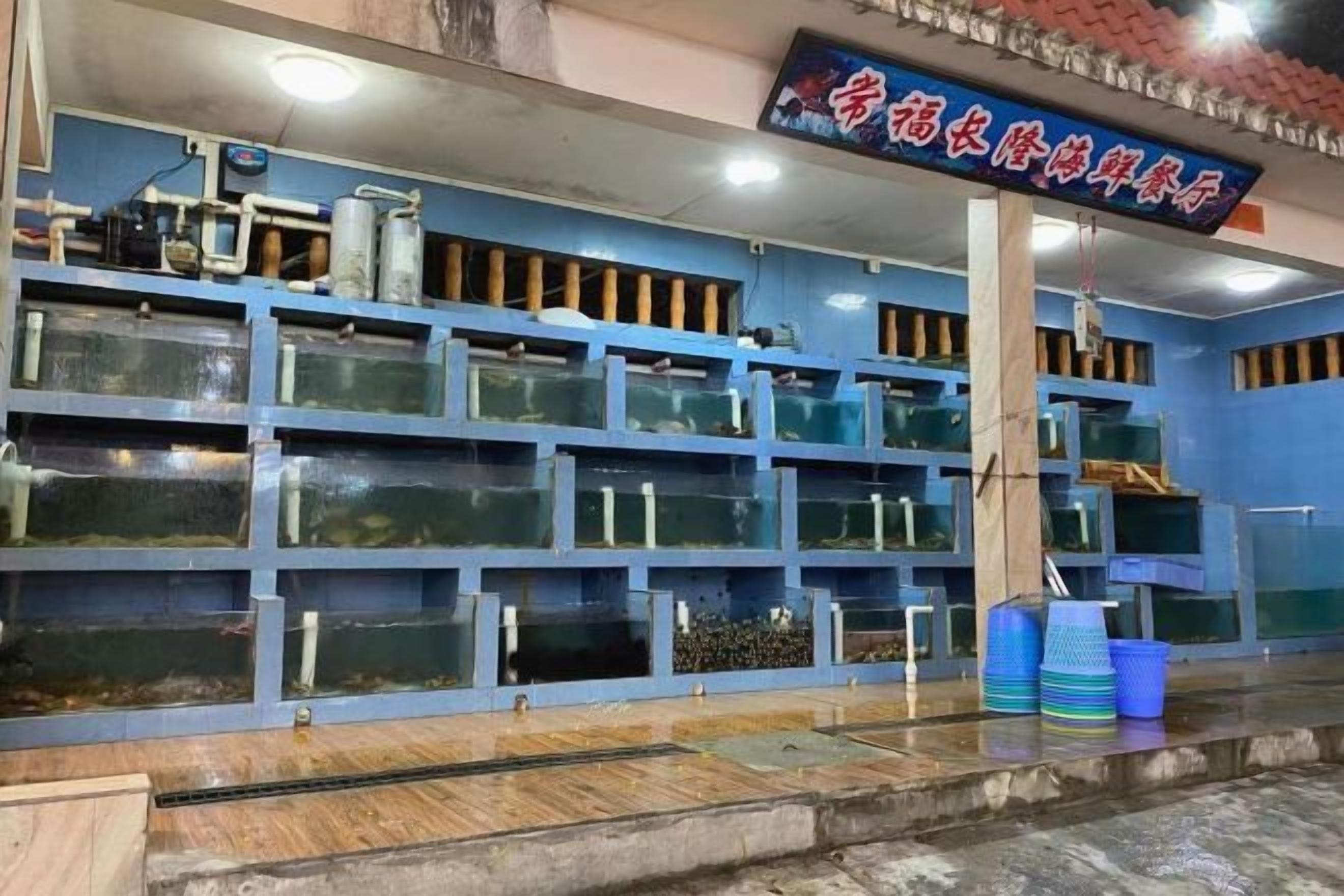 A fish market with multiple aquariums and a sign in a foreign language.