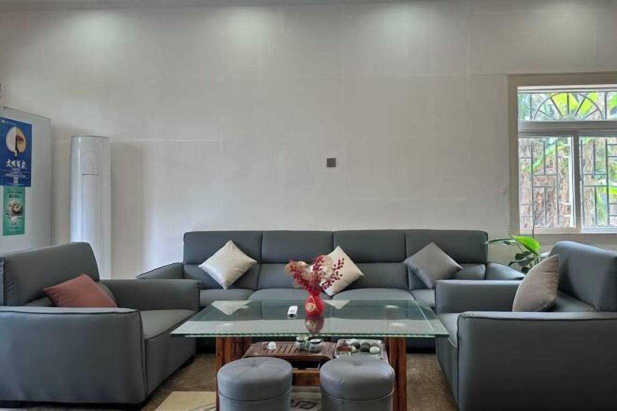 A modern living room with a glass coffee table, grey sofas, and a decorative vase.