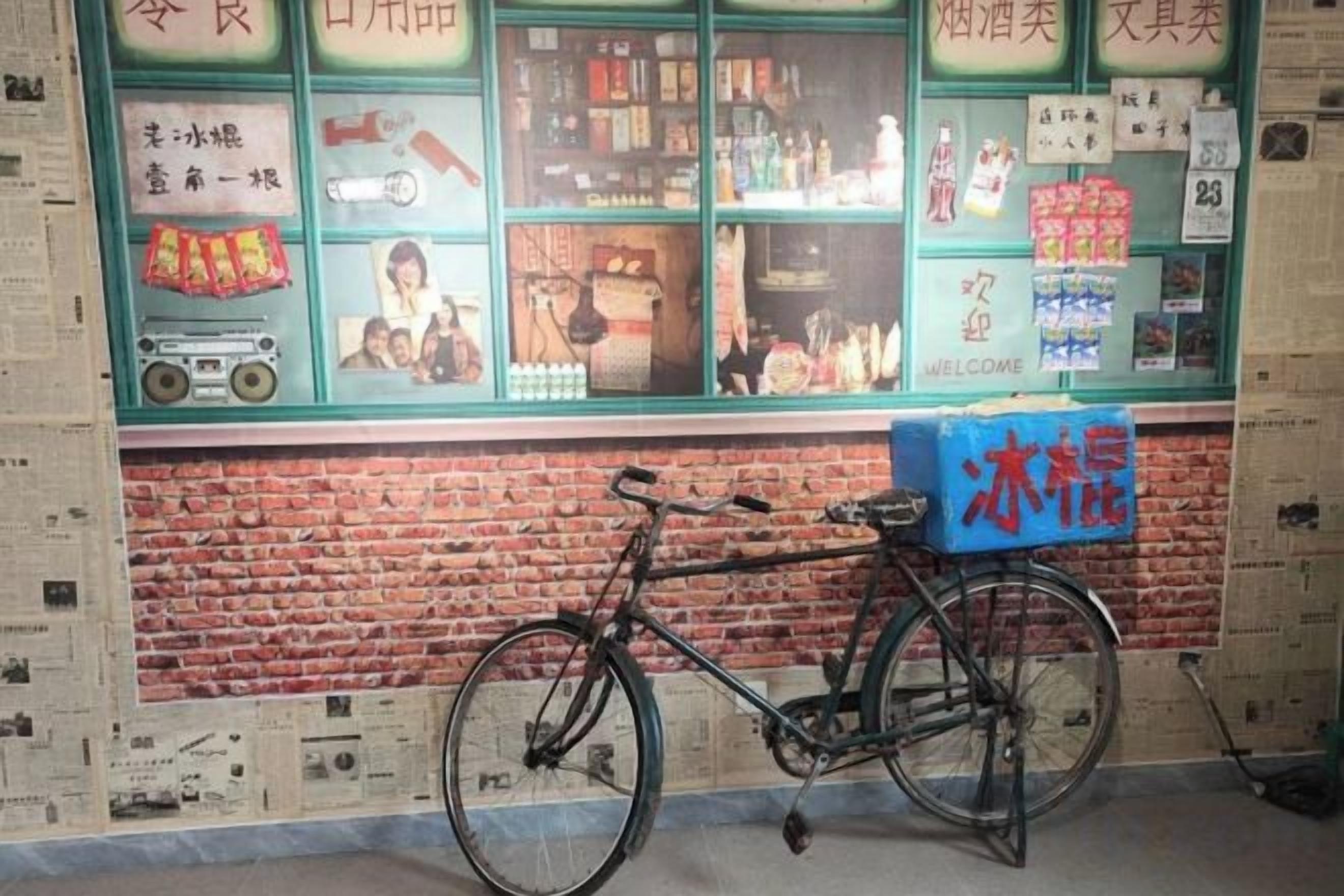 A bicycle parked in front of a store with a brick wall and a window display.