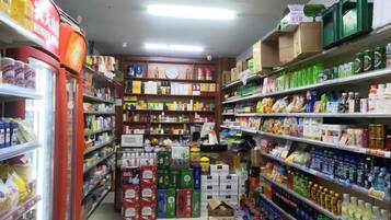 Un rayon d’épicerie où les étagères sont remplies de divers produits, notamment des boissons, des en-cas et des articles ménagers.