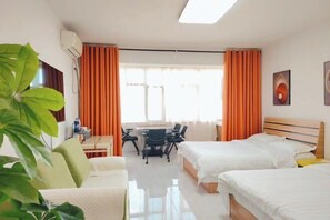Ein Hotelzimmer mit zwei Betten, einem Schreibtisch, Stühlen und einem großen Fenster mit Vorhängen.