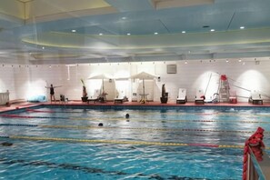 Une piscine intérieure avec des couloirs de nage, des chaises longues et un poste de surveillance pour les sauveteurs.