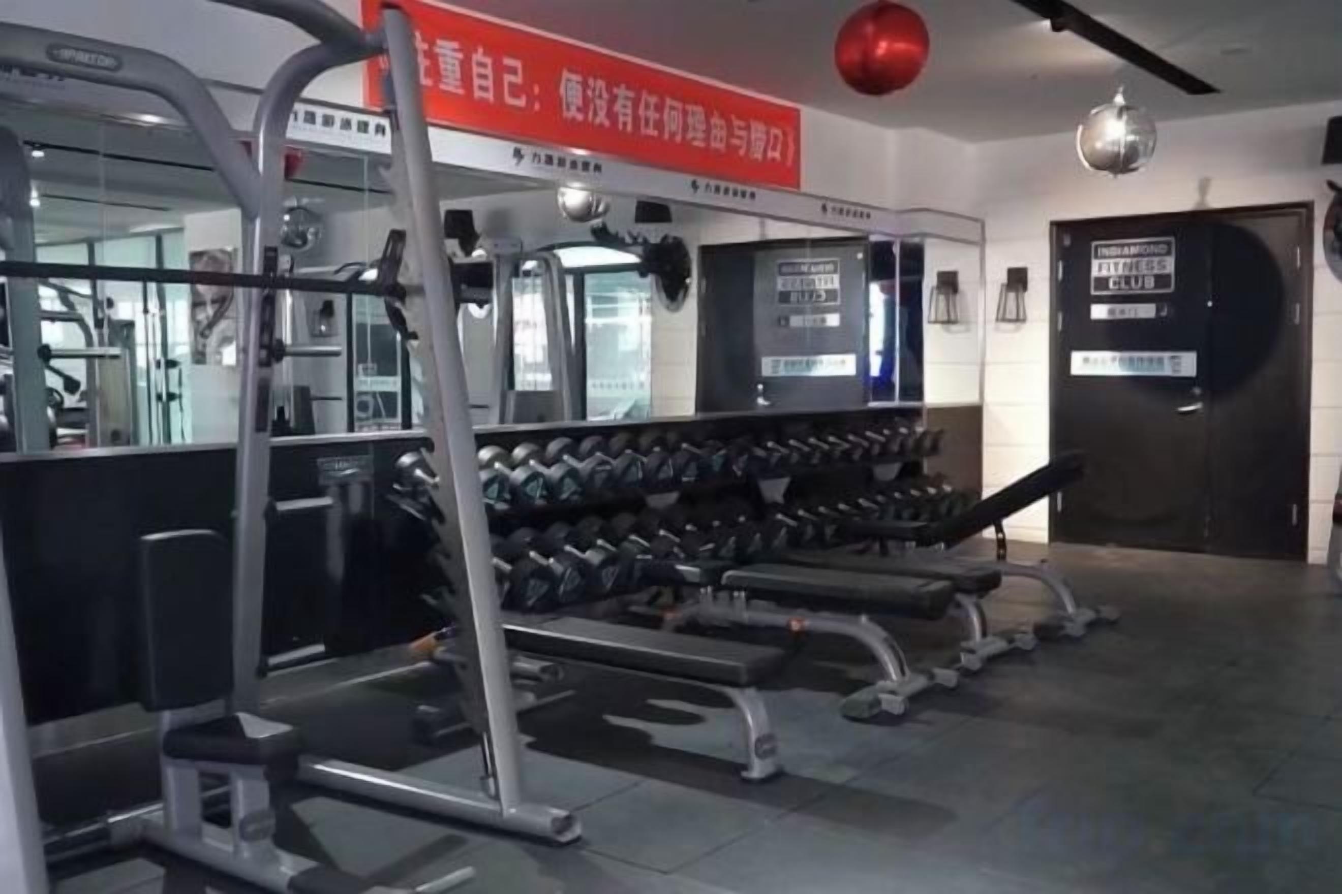 Un gimnasio con equipo de ejercicio, mancuernas y una banca.