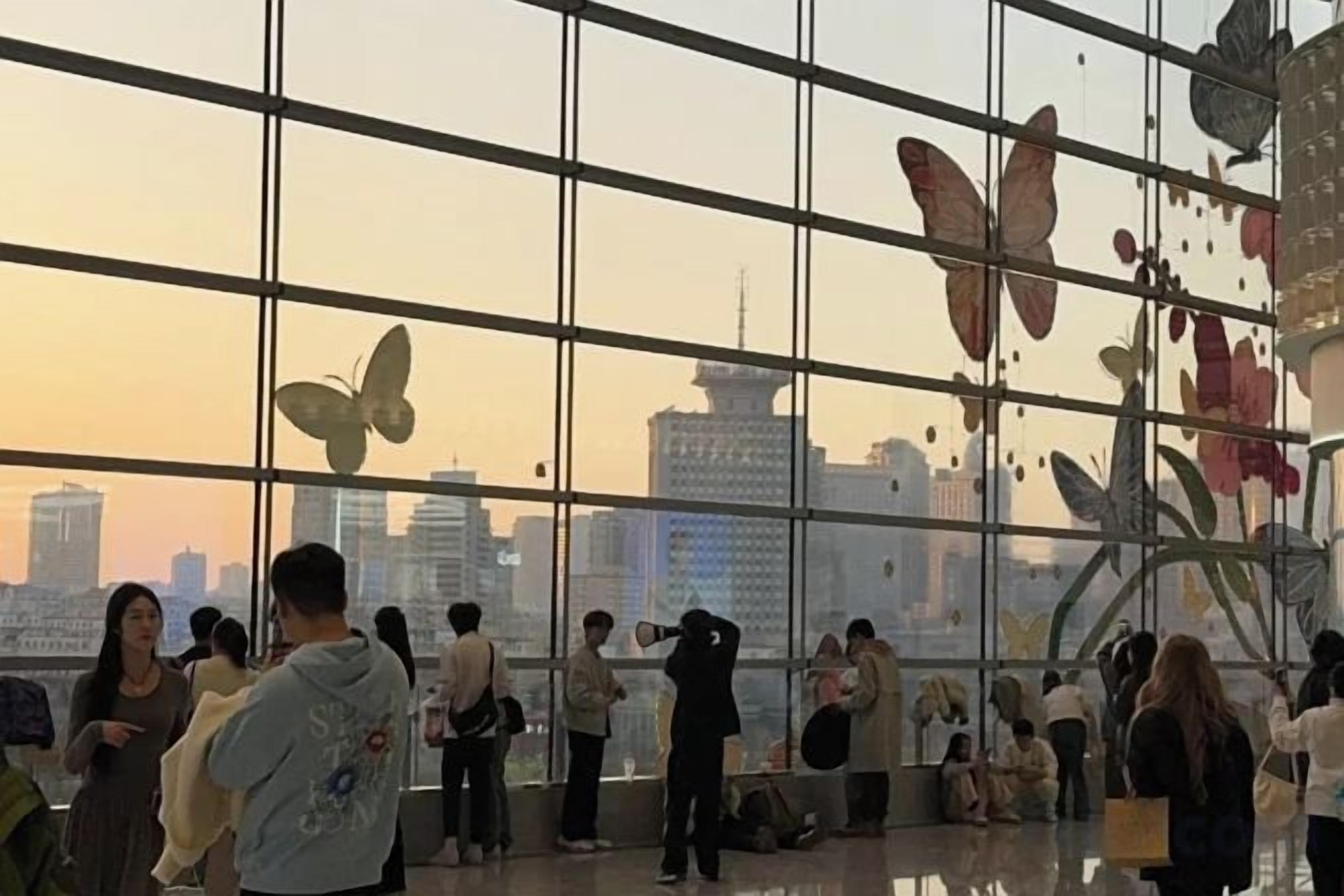A modern interior with large windows, a view of the city skyline, and decorative butterfly motifs.