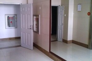 A corridor with a closed door, a wall-mounted sign, and a door with a red circular sticker. - Century Hongyuan Hotel (Chongqing Road Branch) (Changchun)