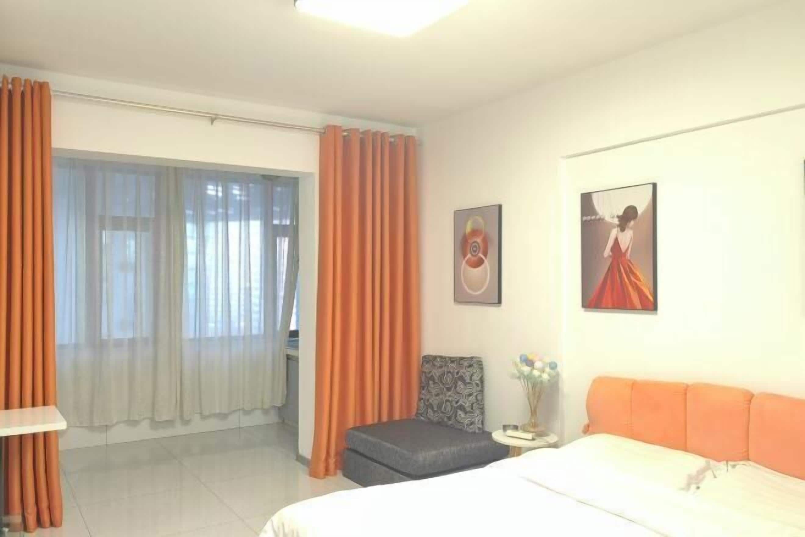 Een hotelkamer met een bed, een klein tafeltje met een vaas, een stoel en twee schilderijen aan de muur.