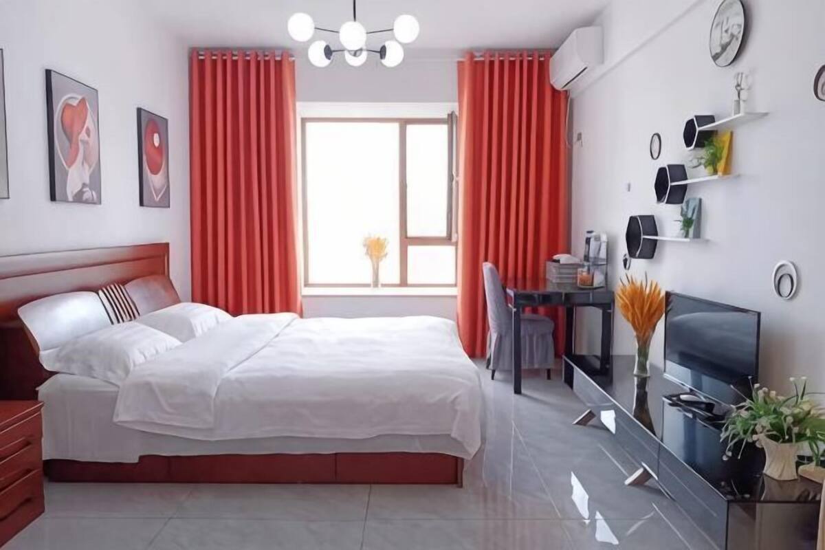A modern bedroom with a large bed, a desk, and a TV.