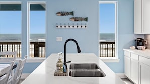 A kitchen with a large island, a view of the ocean, and a fish decoration on the wall. - Fishy Business| Beach Front Oasis!  Sleeps 20! (Bolivar Peninsula)