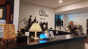 Un comptoir d’accueil d’hôtel avec une pancarte indiquant : « Veuillez passer votre commande et régler ici ».