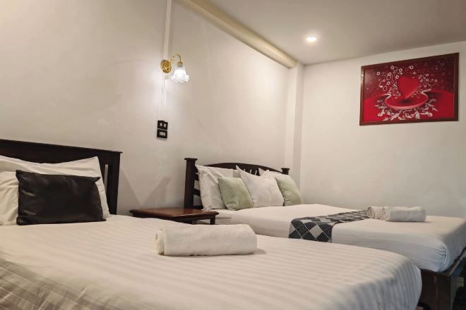 Una habitació d'hotel amb dos llits, una tauleta de nit, una làmpada penjada a la paret i un quadre.