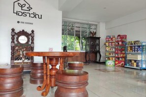 A room with a wooden table and stools, a large mirror, and a window with a view of greenery.