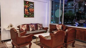 Un salon confortable avec un canapé, des fauteuils et une table basse. Une fenêtre offre une vue sur l’extérieur.