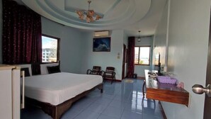 Une chambre d’hôtel avec un lit, des chaises, un bureau, un miroir et une vue sur la ville.