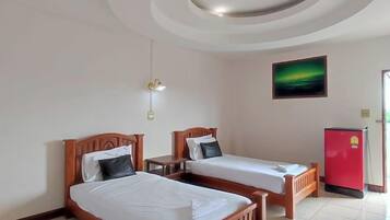 Hotellihuone, jossa on kaksi sänkyä, punainen jääkaappi ja taulu seinällä.
