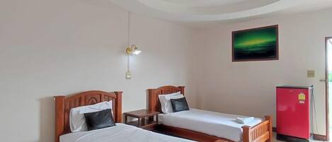 Una habitación de hotel con dos camas, un refrigerador rojo y un cuadro en la pared.