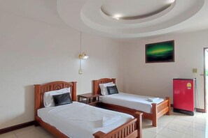 A hotel room with two beds, a red refrigerator, and a painting on the wall.