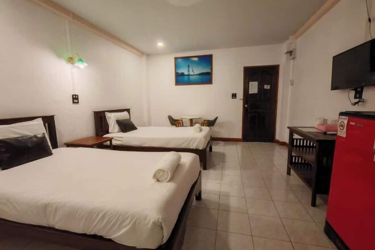 A hotel room with two beds, a small table, a TV, and a door.