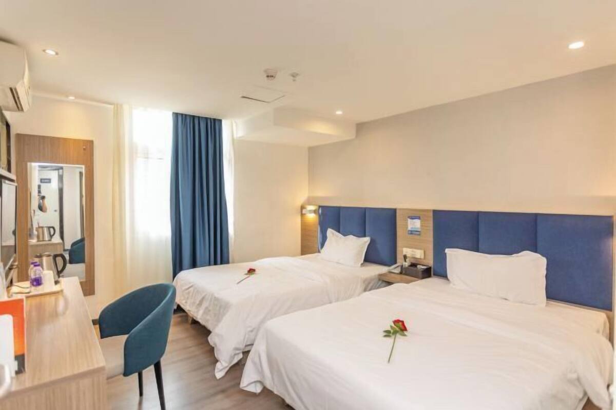 A hotel room with two beds, a desk, and a chair.