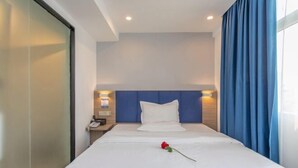 A hotel room with a bed, a nightstand, a phone, and a window with blue curtains. - 7 Days Premium Hotel（Shenzhen North Station Yicheng Center Branch） (Shenzhen)