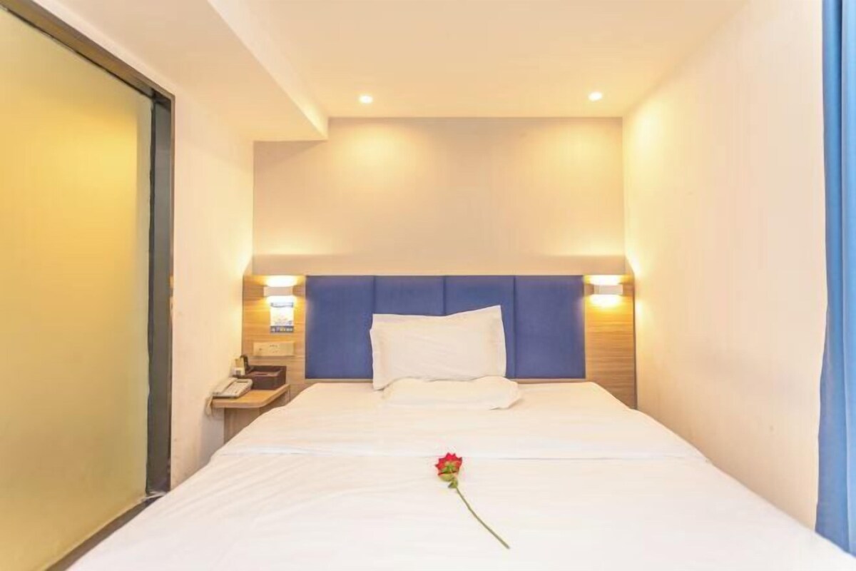 A hotel room with a bed, a nightstand, and a wall-mounted phone.