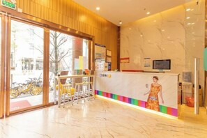 A hotel reception area with a marble counter, a television, and a large window. - 7 Days Premium Hotel(Shenzhen North Station Yicheng Center Branch) (Shenzhen)