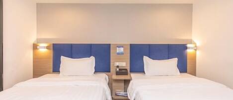 A hotel room with two beds, a wooden headboard, a nightstand, and a wall-mounted charging station.