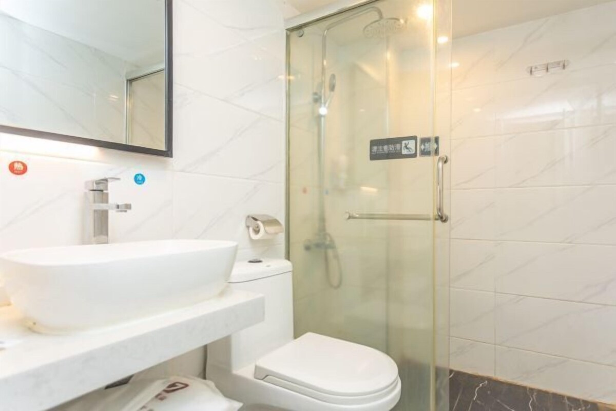 A modern bathroom with a glass-enclosed shower, a white sink, and a toilet.