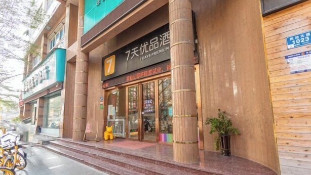 A hotel entrance with a prominent number 7 sign, large wooden pillars, and a glass door entrance. - 7 Days Premium Hotel（Shenzhen North Station Yicheng Center Branch） (Shenzhen)
