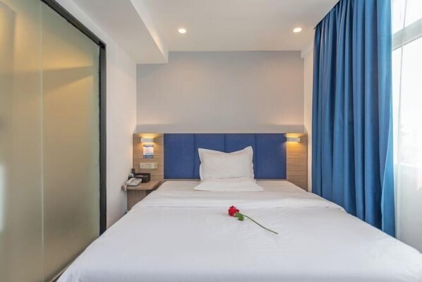 A hotel room with a bed, a nightstand, a phone, and a window with curtains. - 7 Days Premium Hotel（Shenzhen North Station Yicheng Center Branch） (Shenzhen)