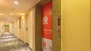 A hotel corridor with a patterned carpet, a red sign with white text, and an elevator control panel. - 7 Days Premium Hotel（Shenzhen North Station Yicheng Center Branch） (Shenzhen)