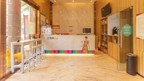 A hotel reception area with a marble floor, wooden paneling, a reception desk, and a bar area with stools. - 7 Days Premium Hotel（Shenzhen North Station Yicheng Center Branch） (Shenzhen)