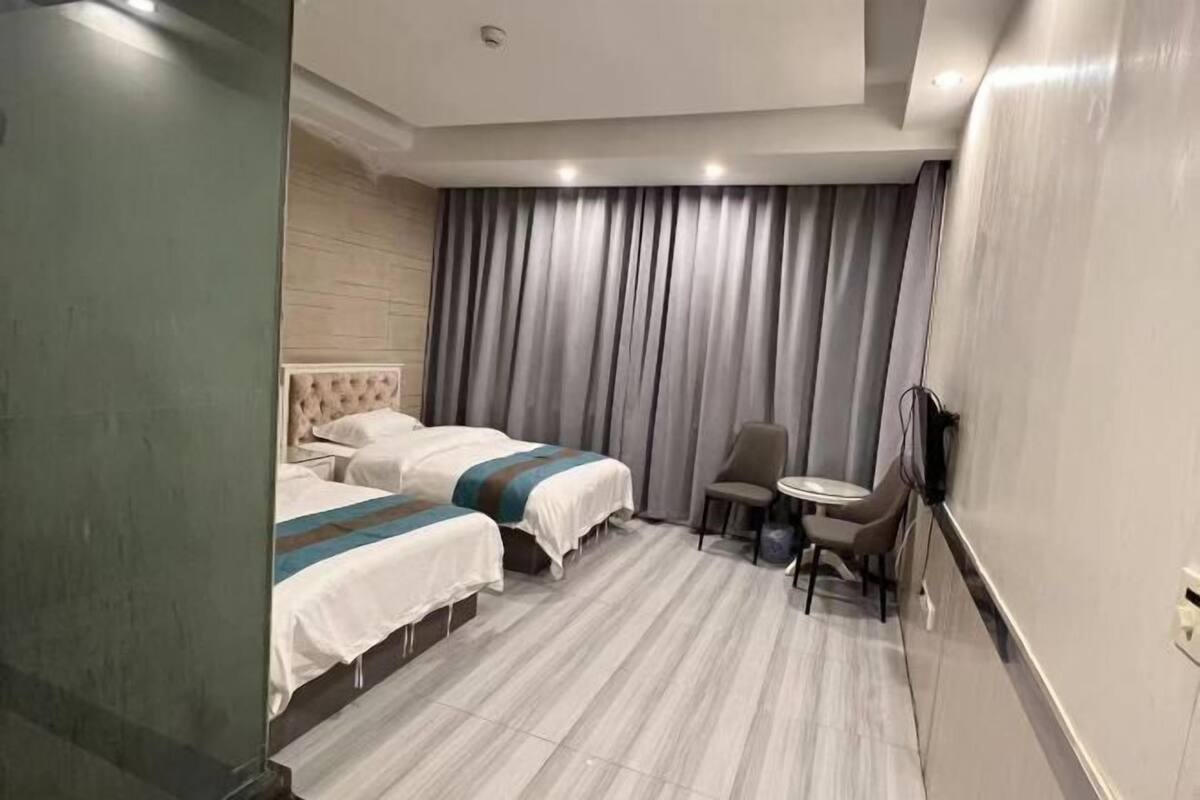 Una habitación de hotel con dos camas, una mesita, una silla y un televisor.
