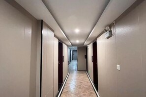 Un couloir bordé de portes des deux côtés, menant à une pièce située au fond.