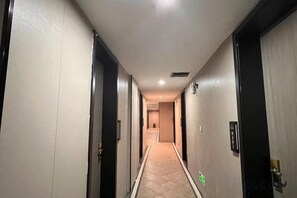Un couloir étroit, avec des portes des deux côtés, qui mène à différentes pièces.