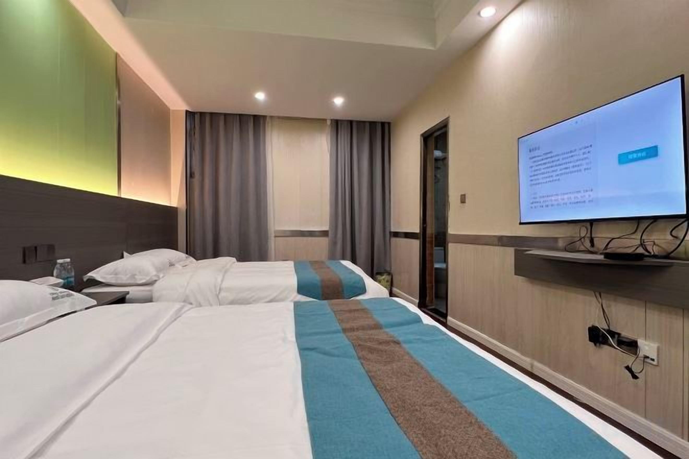 A hotel room with two beds, a television, and a window with curtains.