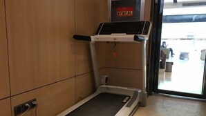 A treadmill in a room with wooden walls and a tiled floor. - IU Hotels (Jingshan)