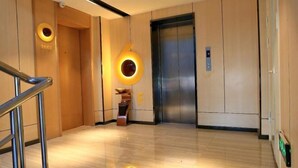 A modern elevator with a metallic finish and a digital display. - IU Hotels (Jingshan)