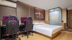 A hotel room with a bed, two gaming chairs, a desk, and a large abstract painting. - IU Hotels (Jingshan)