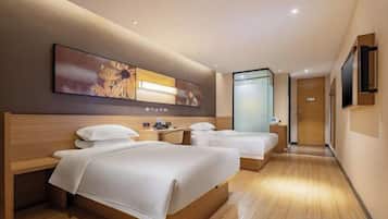 A hotel room with two beds, a wooden headboard, a large artwork, a bedside table, and a TV.