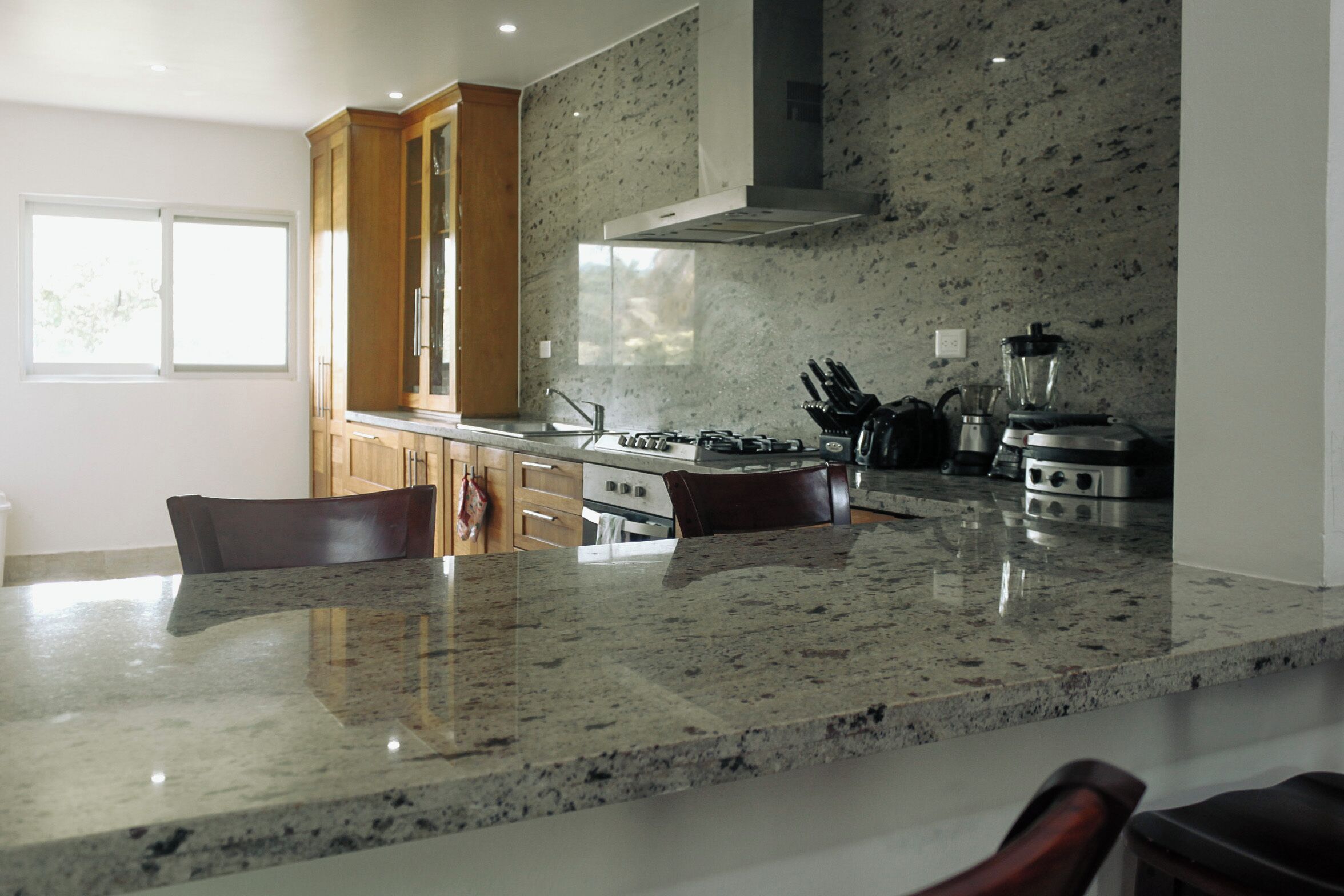 Una cocina moderna con encimeras de granito, electrodomésticos de acero inoxidable y armarios de madera.