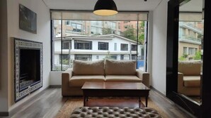 A modern living room with a sofa, coffee table, and fireplace. - Apartamentos El Árbol (Bogotá)