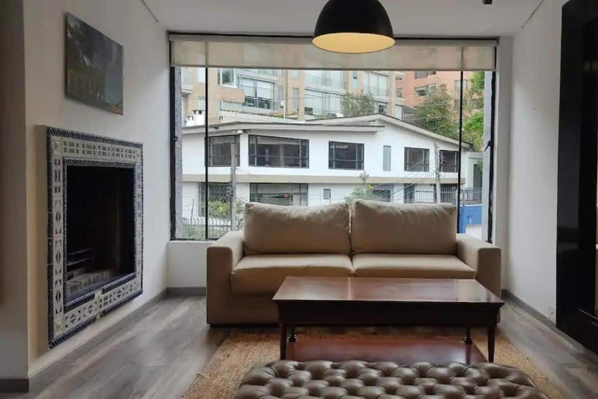 A modern living room with a sofa, coffee table, and fireplace.